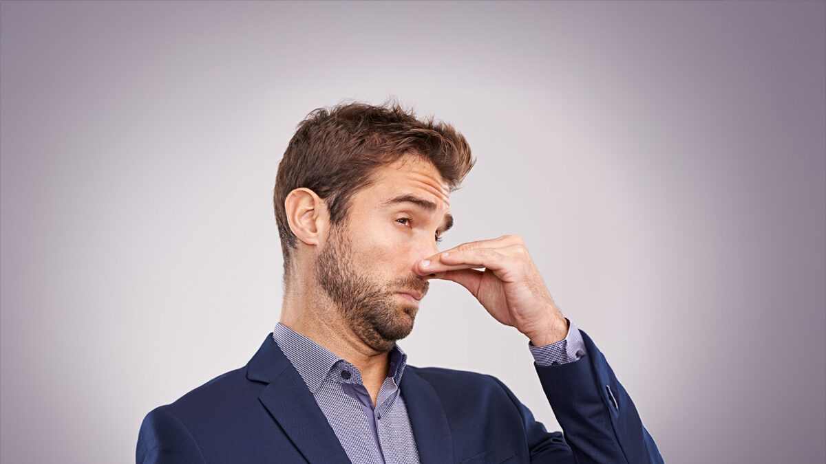 man plugging nose due to grease trap odor